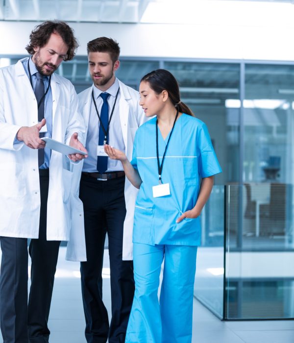 Doctor holding digital tablet having a discussion with colleagues