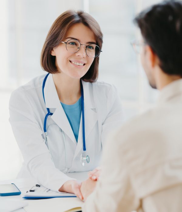 Female doctor reassures her male patient, hold hand and talk calmly about illness cure